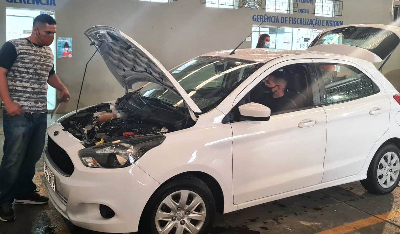 um homem olha para um carro que está com o capô aberto